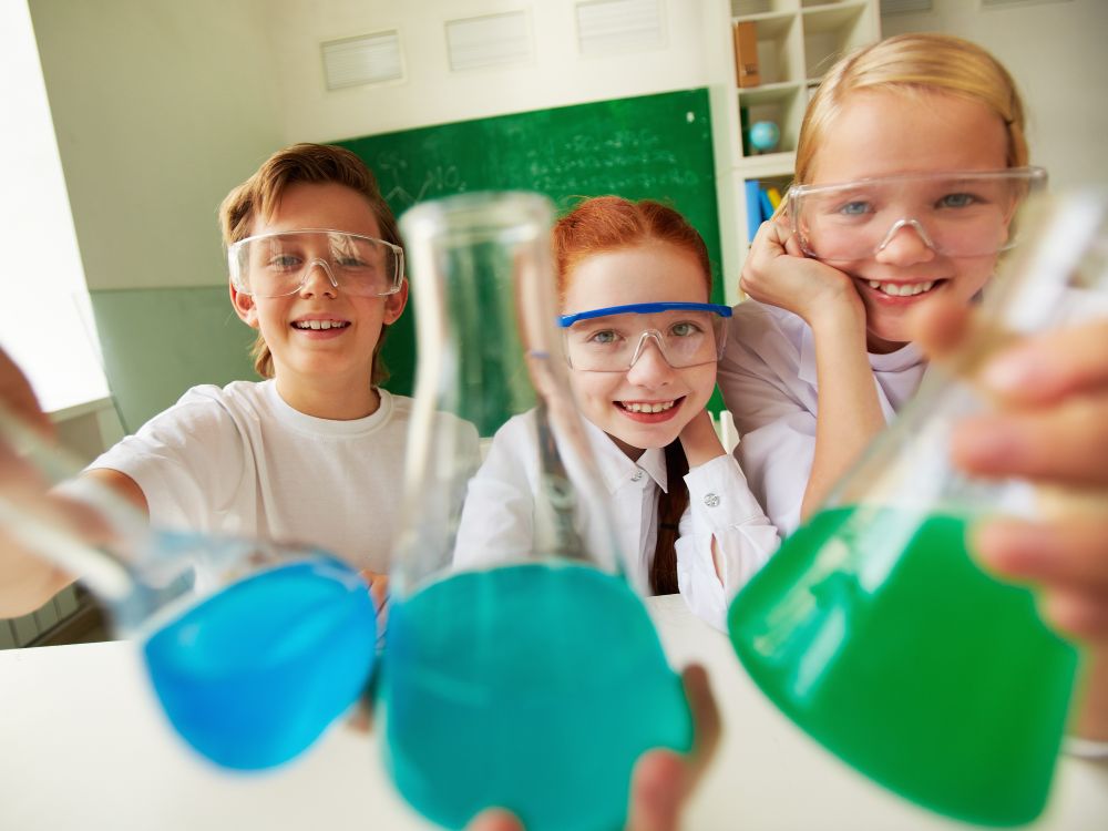 Hands-On Science Education at Pointe Schools Engaged students happily conducting a science experiment with flasks at Pointe Schools.